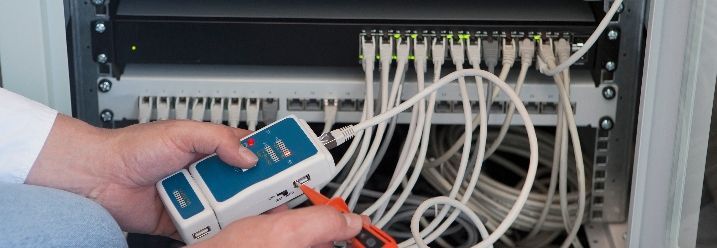 Person überprüft Netzwerkkabel an Serverschrank